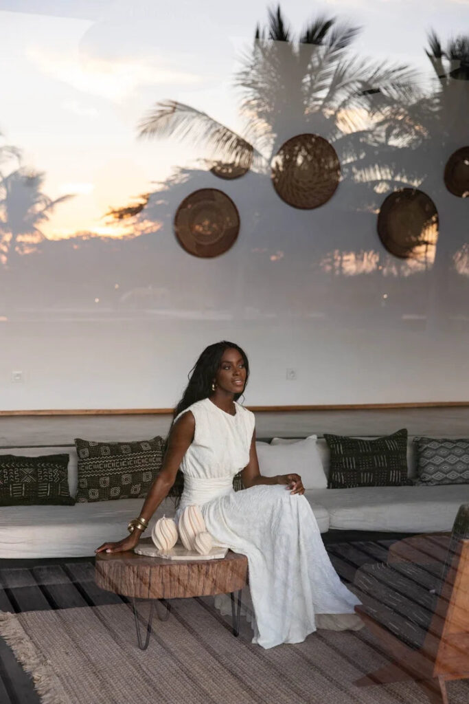 Woman in a white dress seated in the Éluwa studio at sunset
